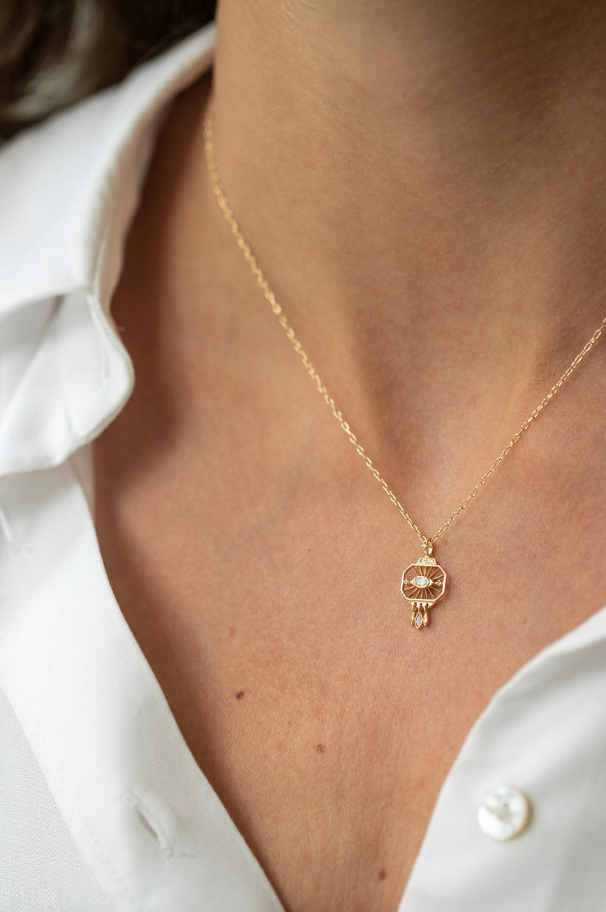 Woman wearing a dream maker open-eye diamond pendant necklace in 14k gold by Celine Daoust.