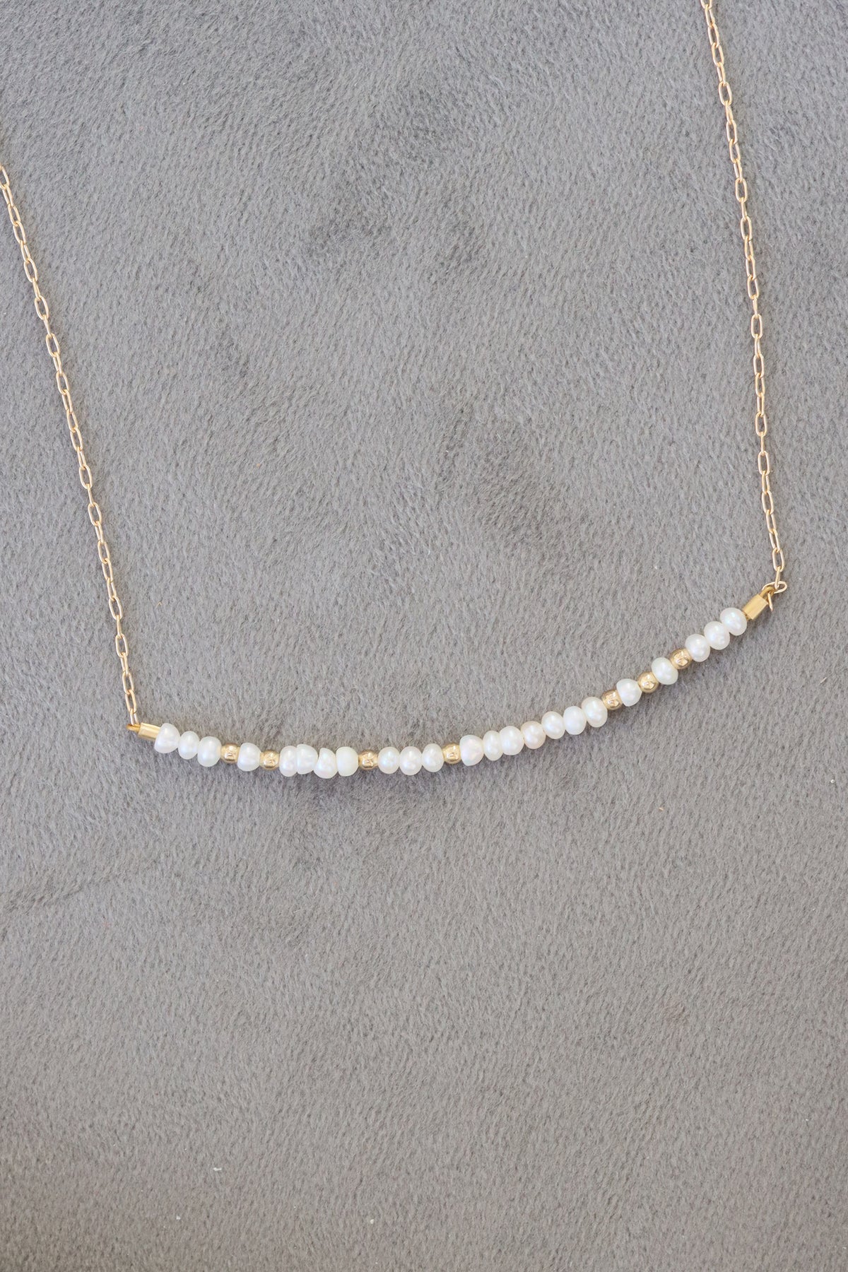 June birthstone bar necklace with freshwater pearl beads on a gold chain.