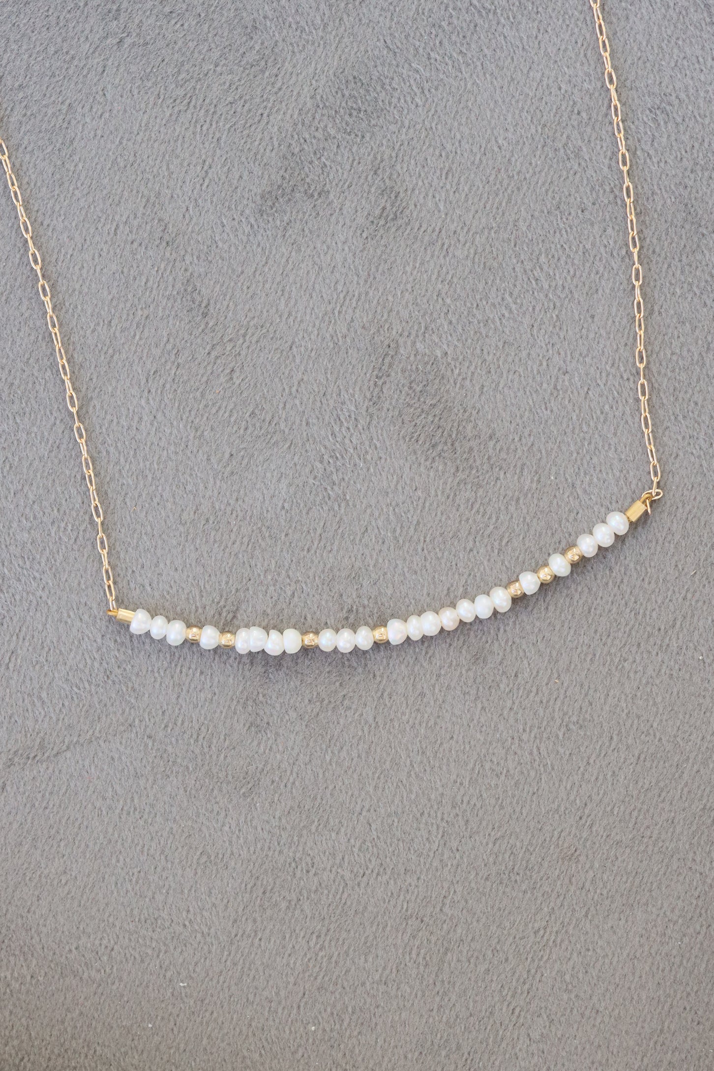 June birthstone bar necklace with freshwater pearl beads on a gold chain.