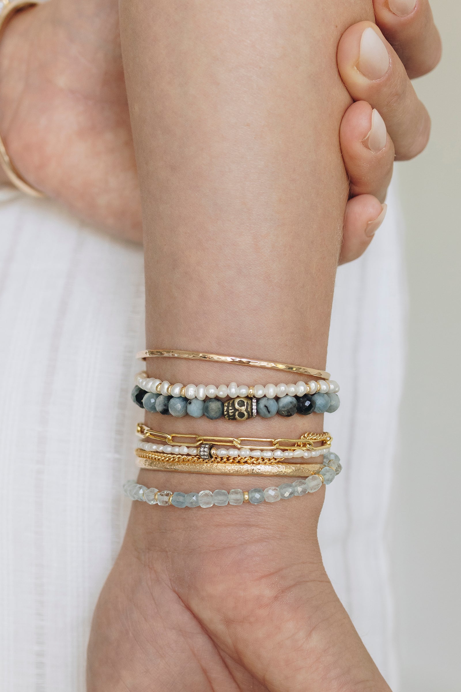 Faceted aquamarine gemstone bracelet with brass skull charm and white topaz pavé accents.