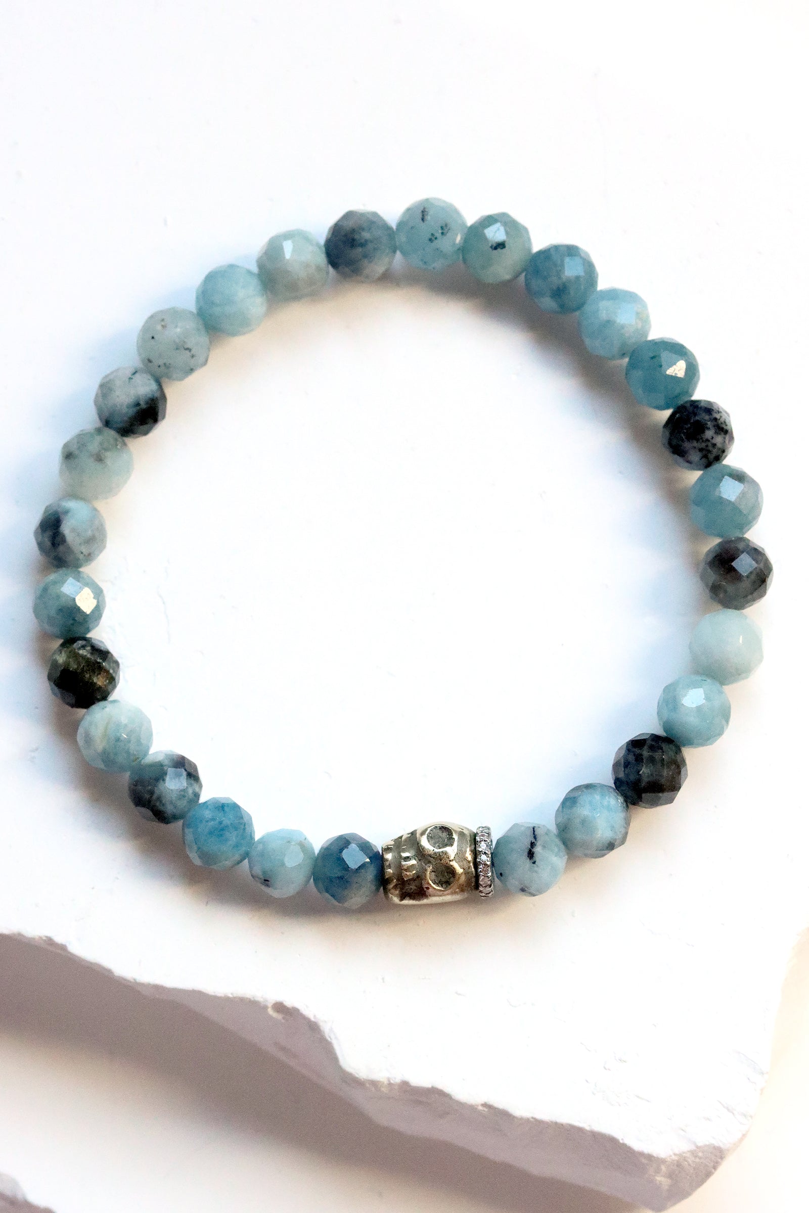 Faceted aquamarine gemstone bracelet with brass skull charm and white topaz pavé accents.