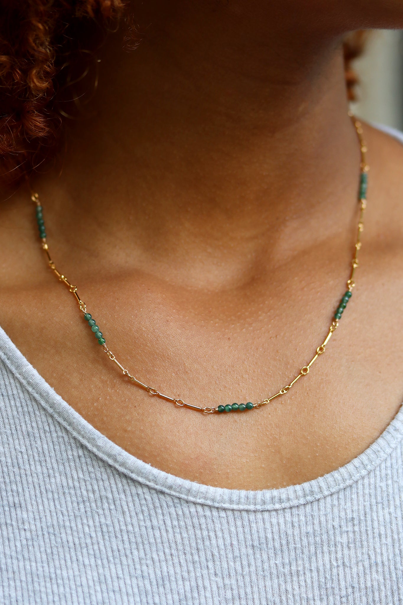 Gold necklace with green jade  beads on a beige background