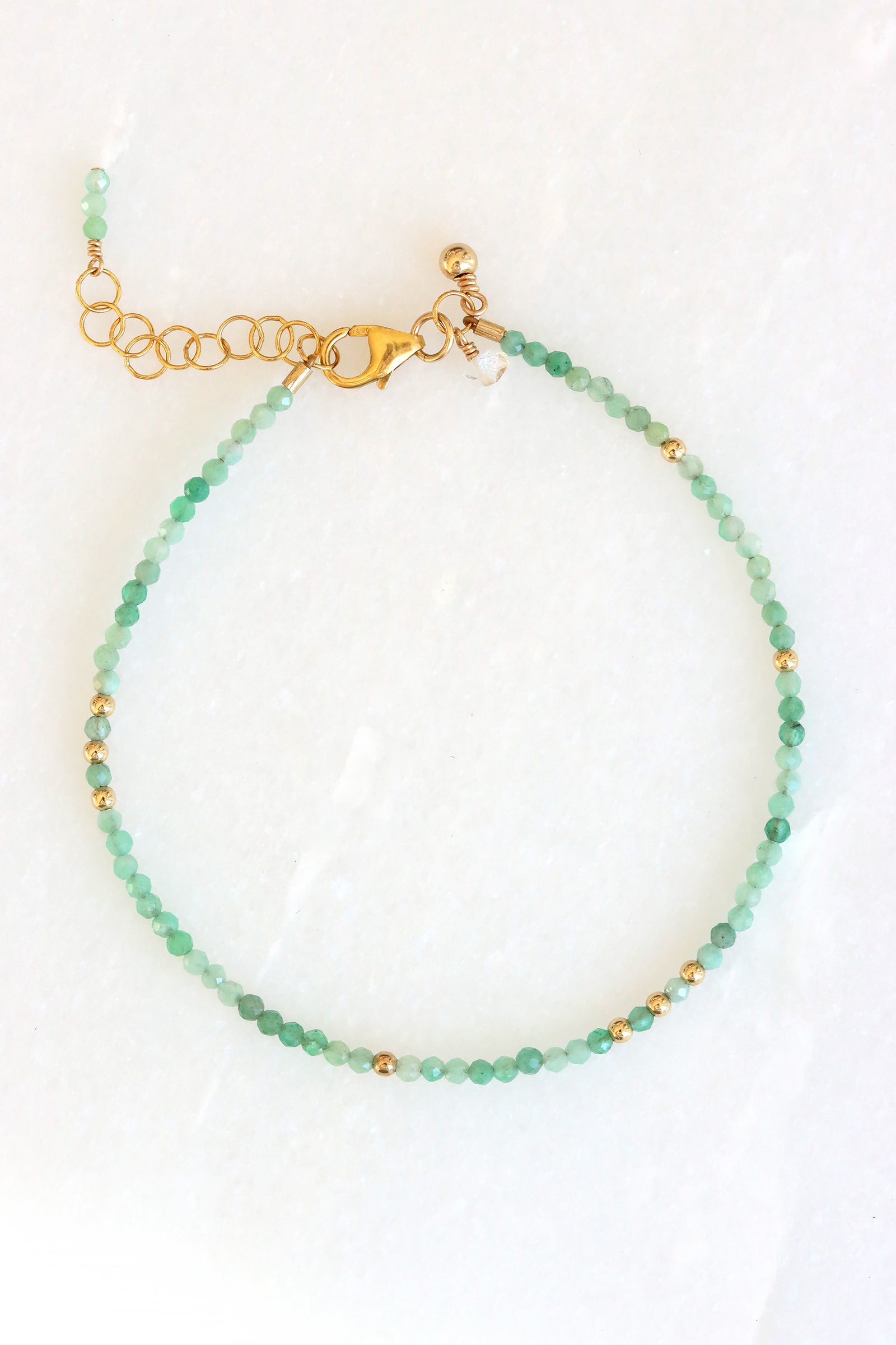 Emerald birthstone charm bracelet with faceted emerald beads and gold accents, shown on white background.