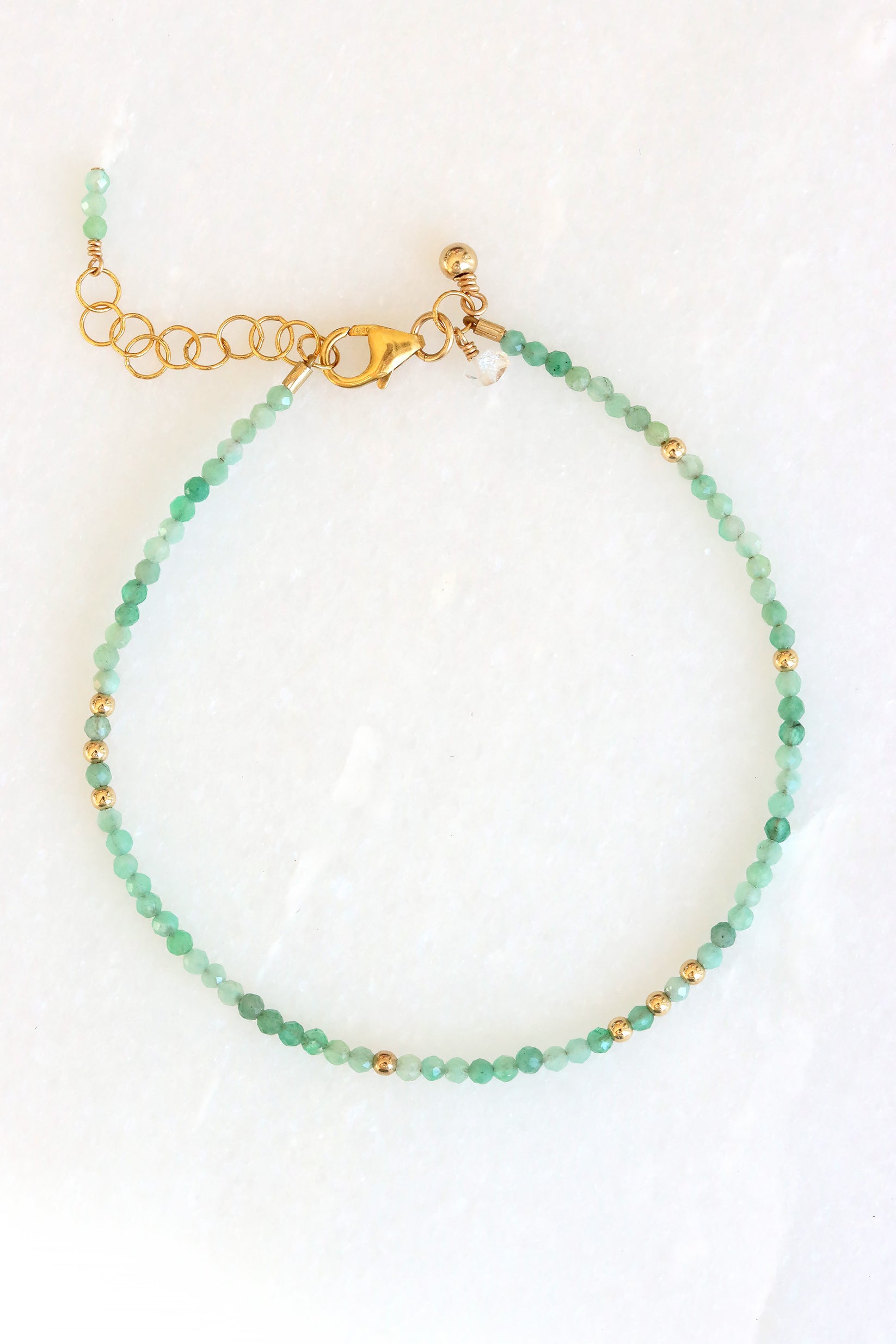Emerald birthstone charm bracelet with faceted emerald beads and gold accents, shown on white background.