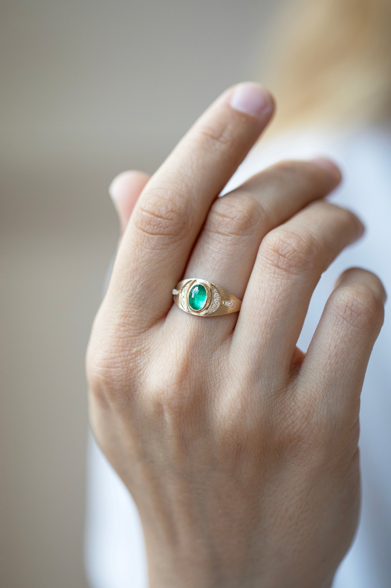 Woman wearing an emerald and diamond moons ring in 14k yellow gold by Celine Daoust.