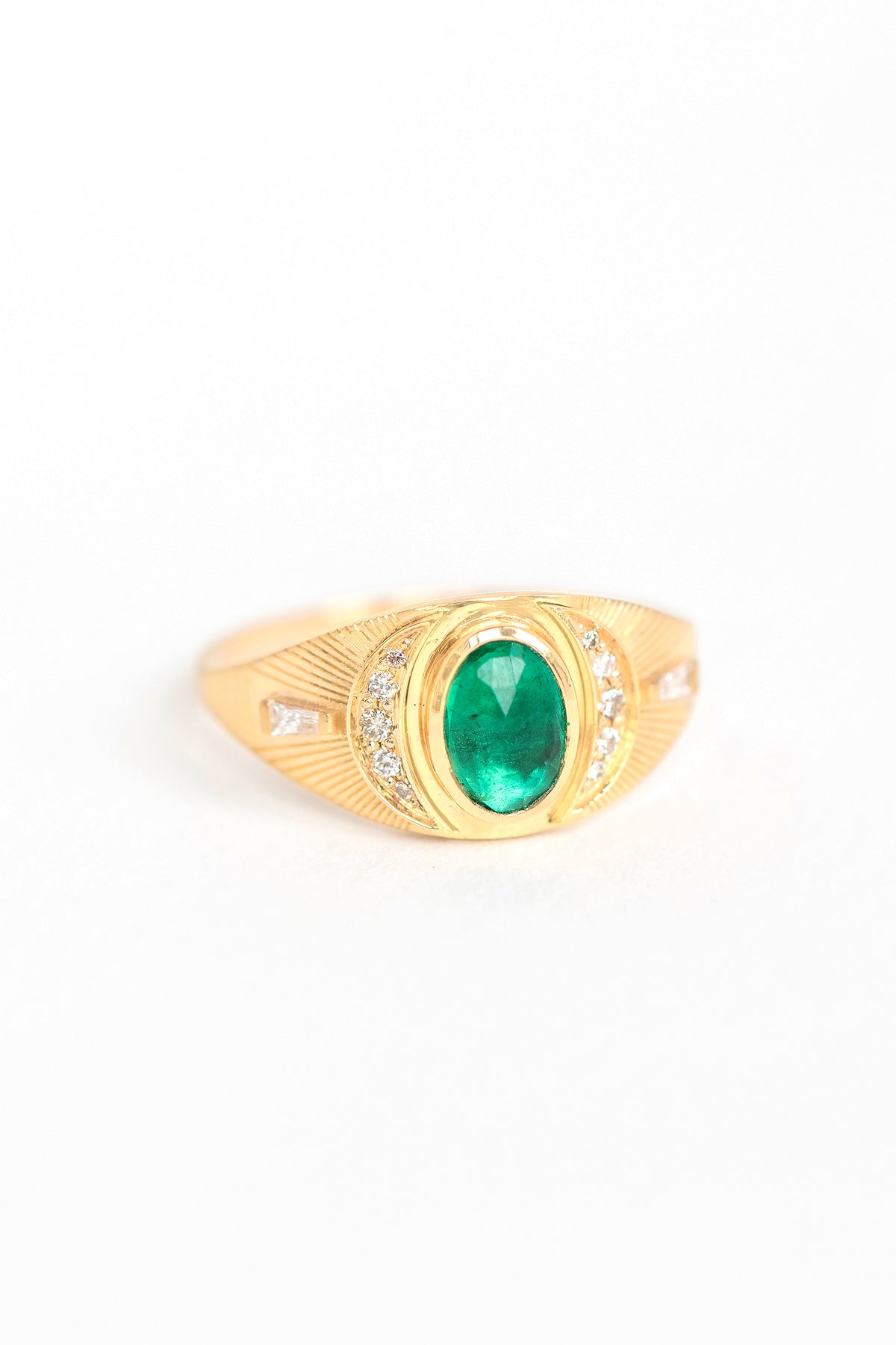 Close-up of emerald and diamond crescent moon ring in 14k gold.