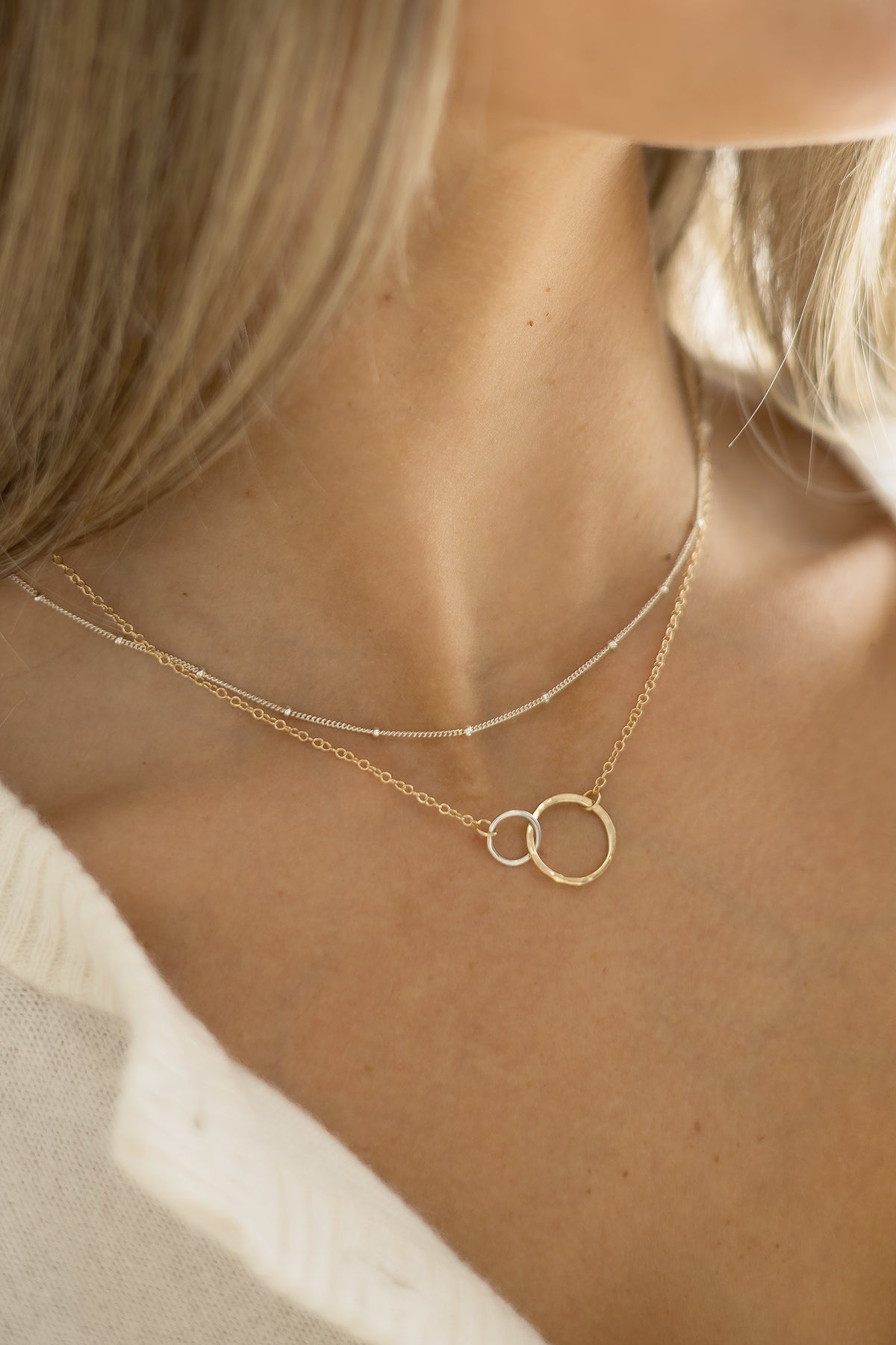 Model wearing the Petite Encircle Necklace with two interlocking hand-hammered gold/silver rings on a delicate gold chain.