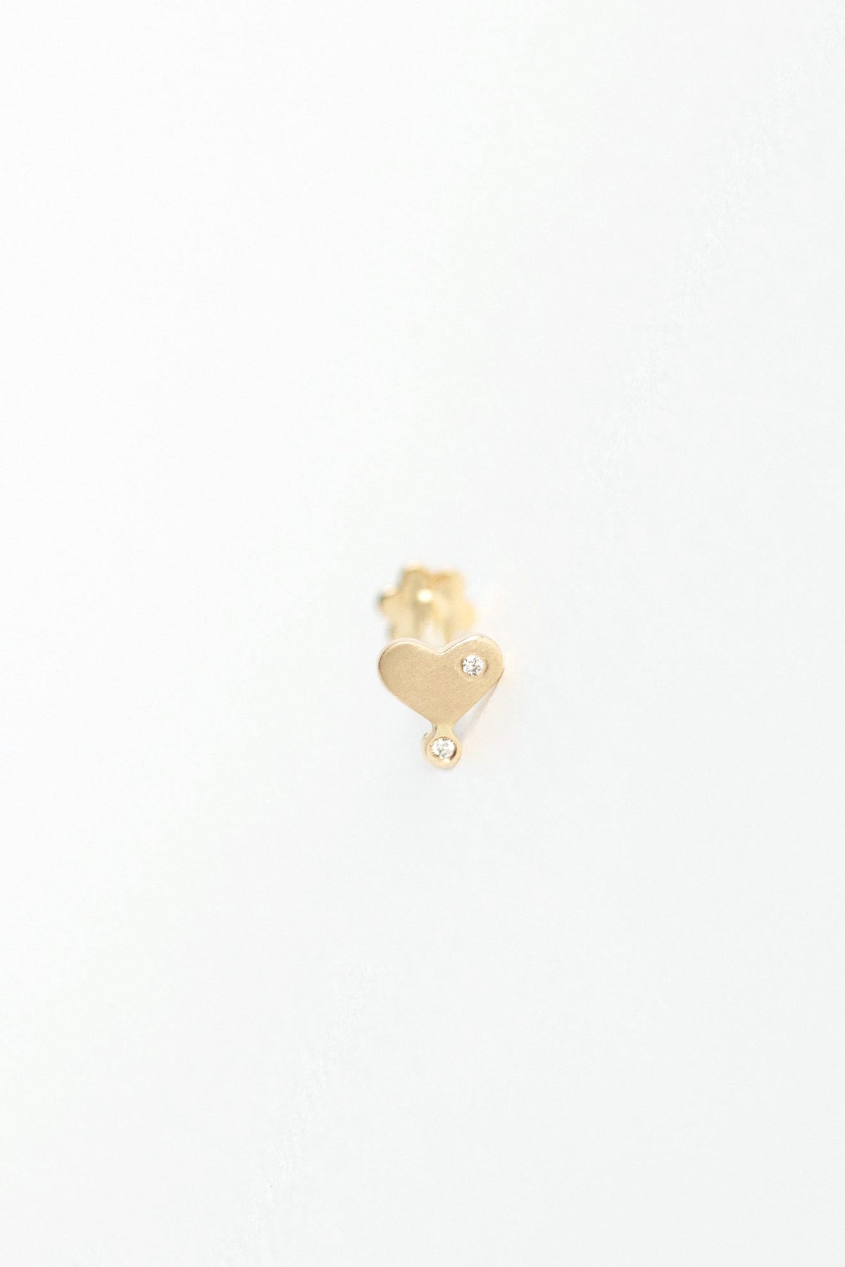 Diamond heart stud flatback piercing in 14k light yellow gold by Celine Daoust.