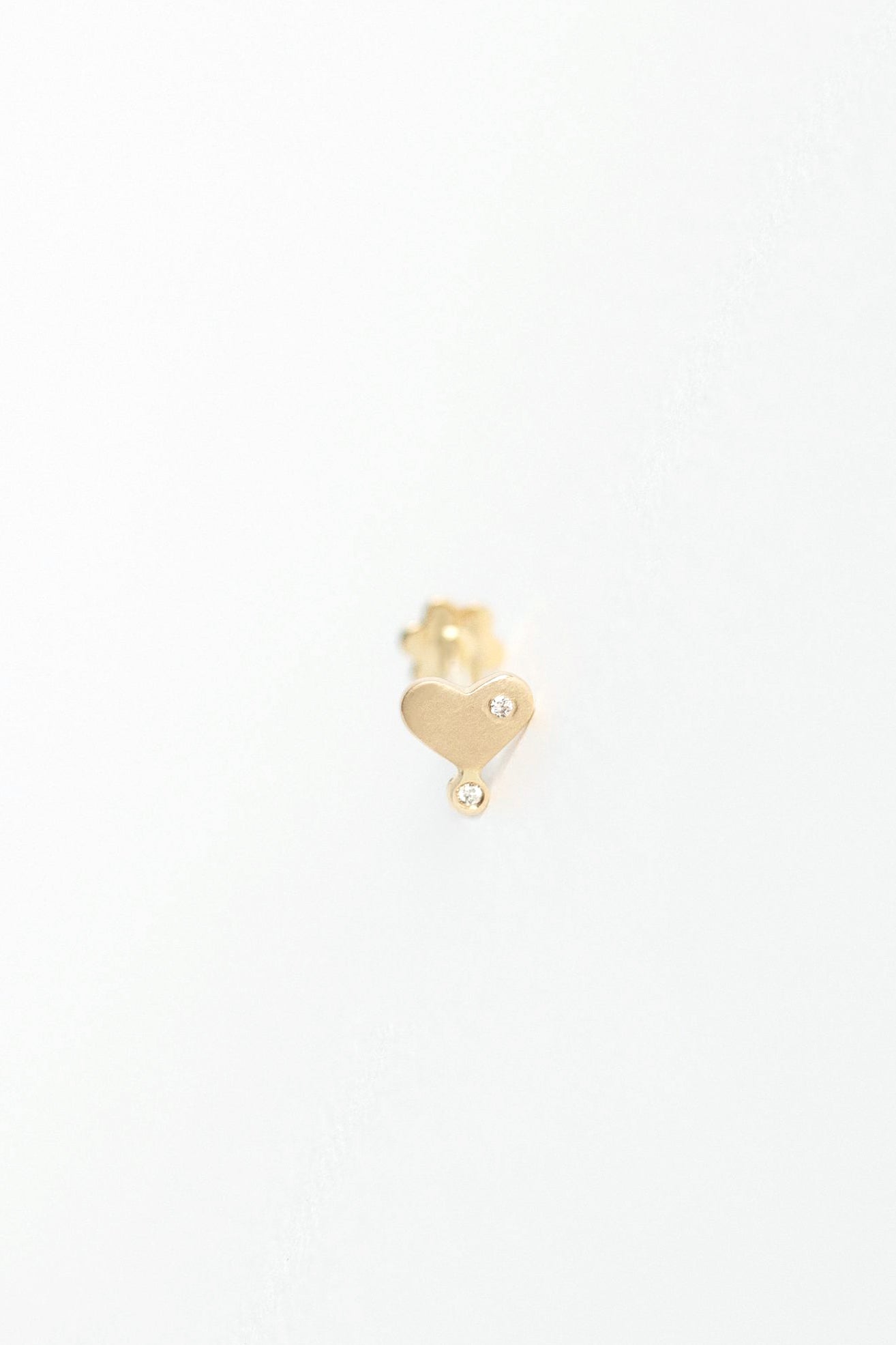 Diamond heart stud flatback piercing in 14k light yellow gold by Celine Daoust.