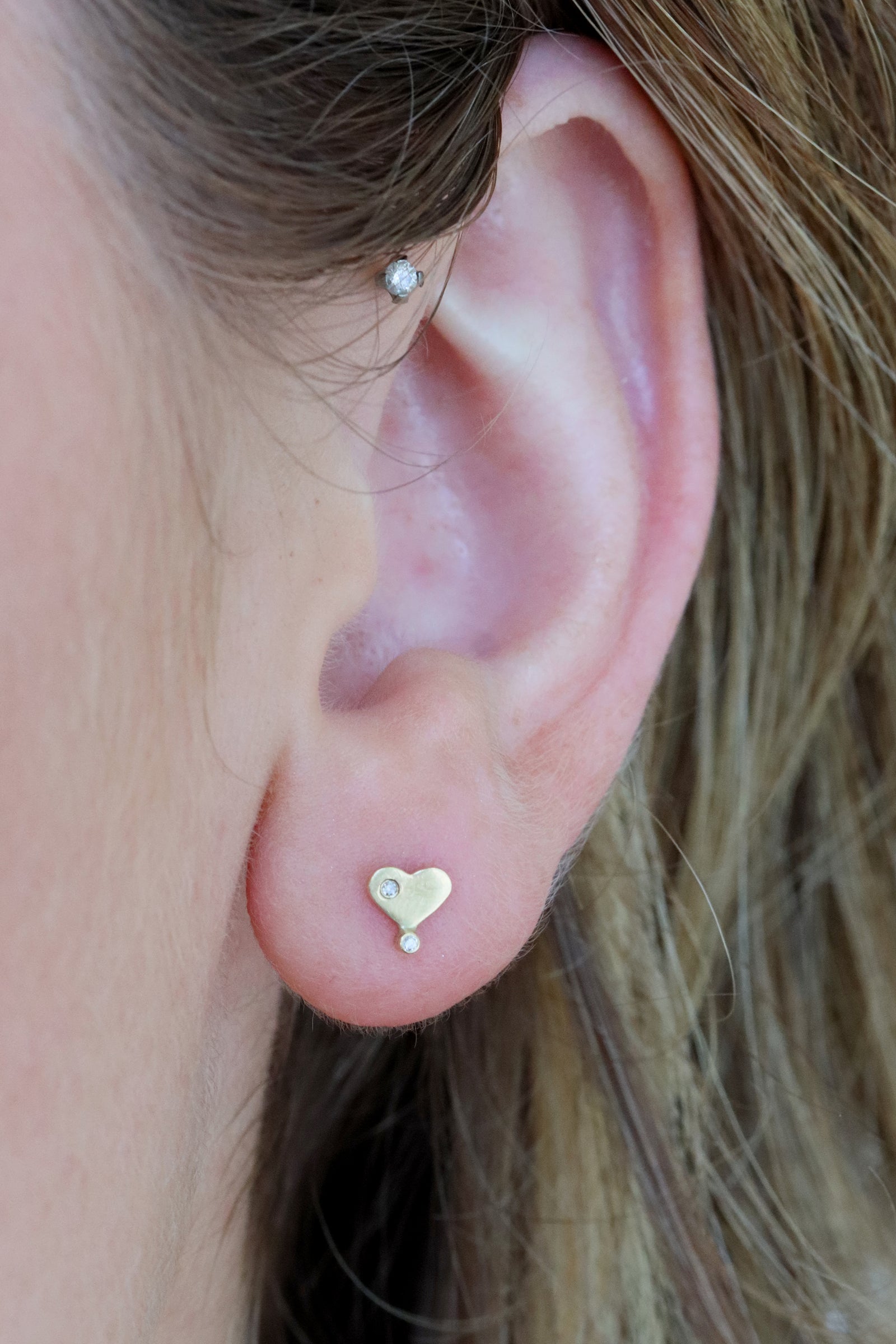Diamond heart stud flatback piercing in 14k light yellow gold by Celine Daoust.