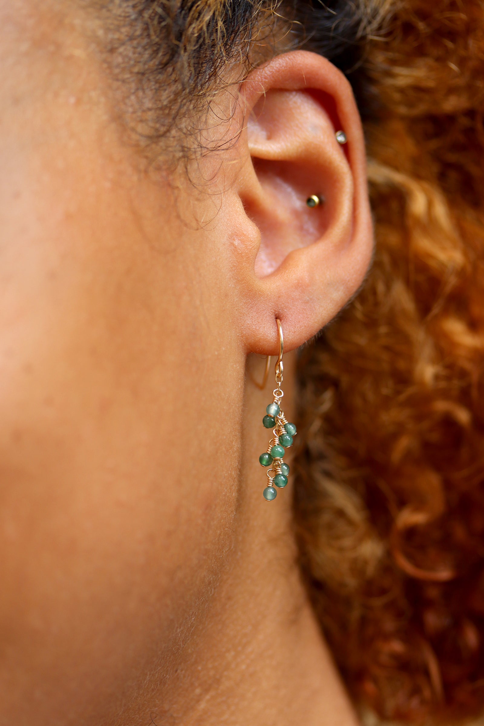 Jade Breeze Earrings with wire-wrapped Guatemalan jade beads on gold hook earrings, on a white surface