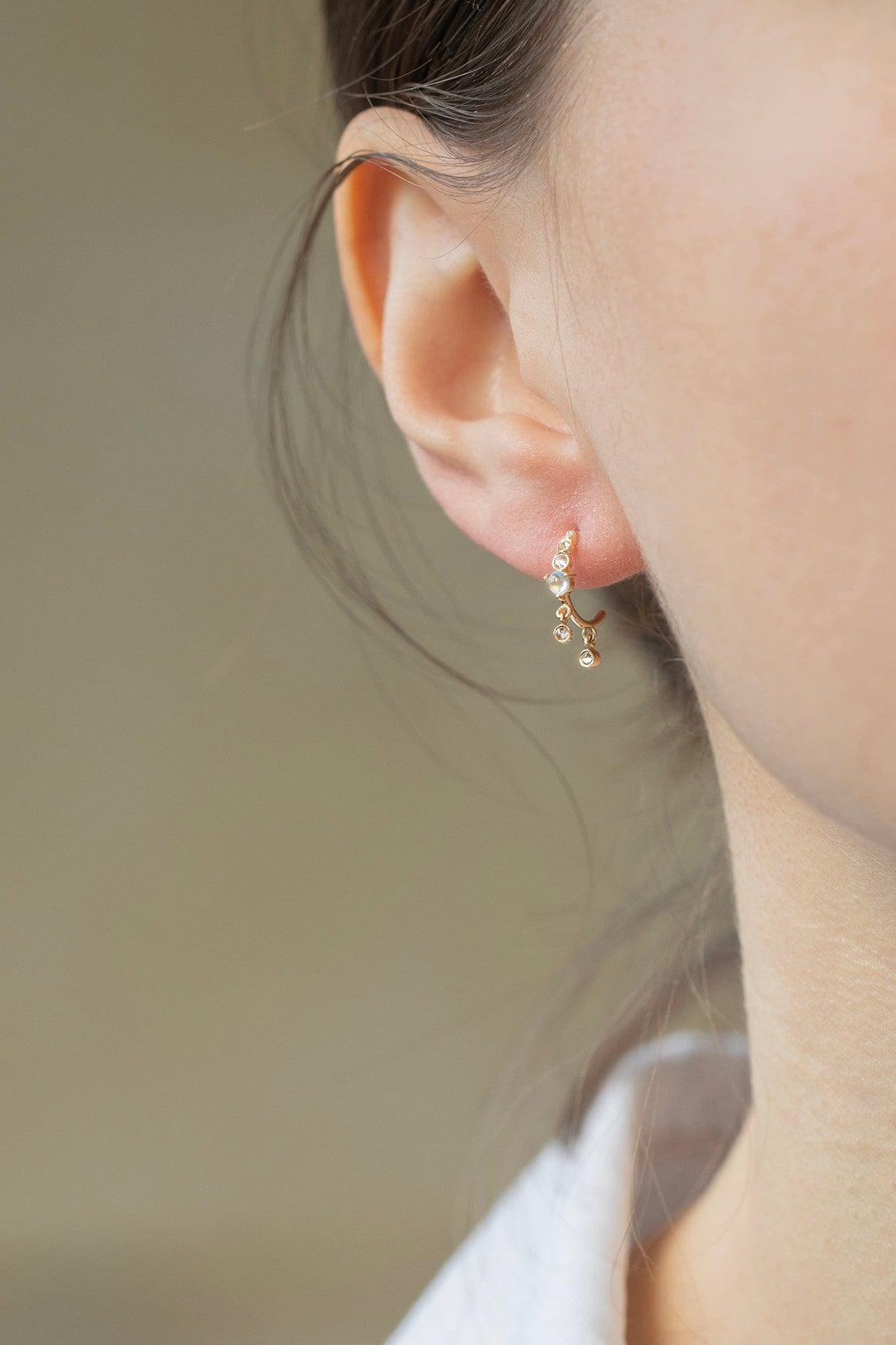 Close-up of moonstone and diamond hoop earring in 14k gold.