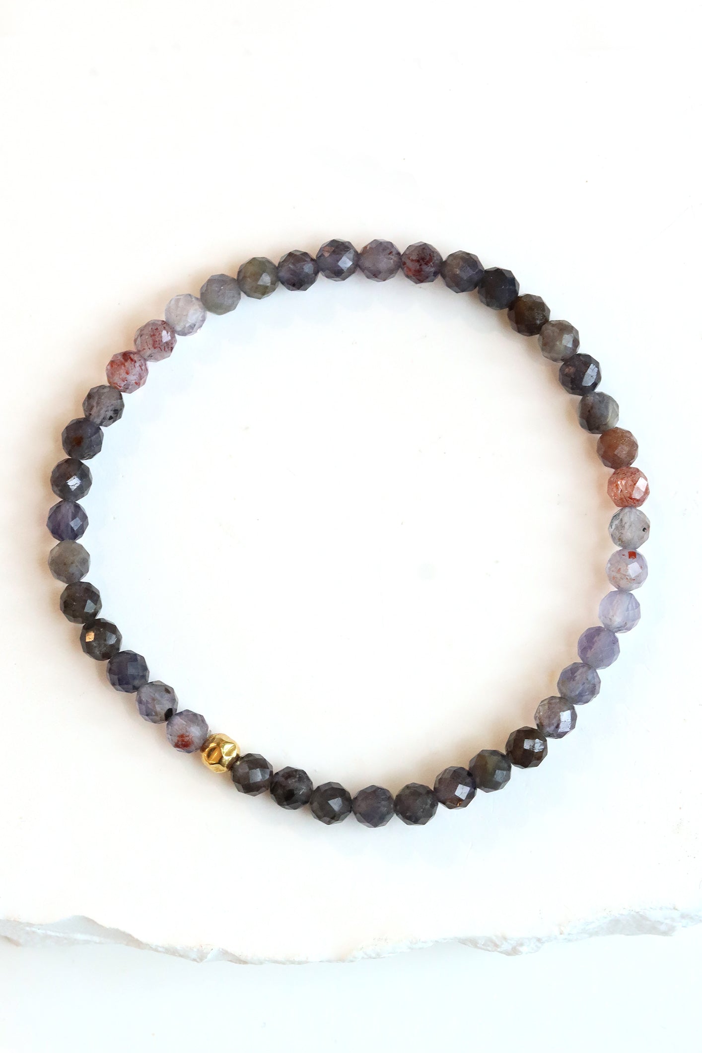 Sunstone iolite Petal Bracelet with faceted plum and grey beads and a gold fill hammered ball accent, photographed on a white surface.