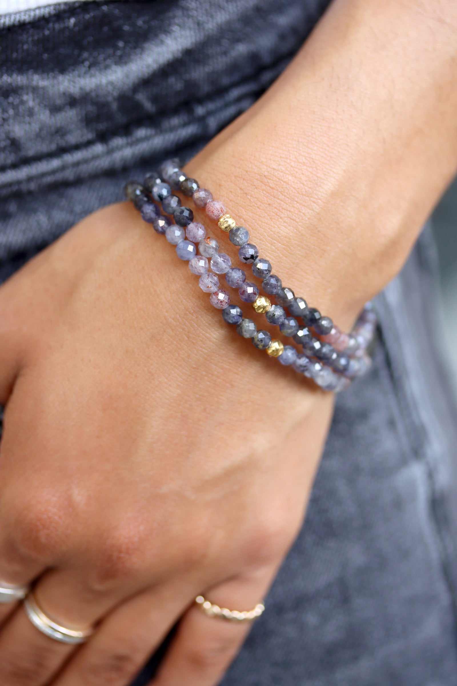Sunstone iolite Petal Bracelet with faceted plum and grey beads and a gold fill hammered ball accent, photographed on a white surface.