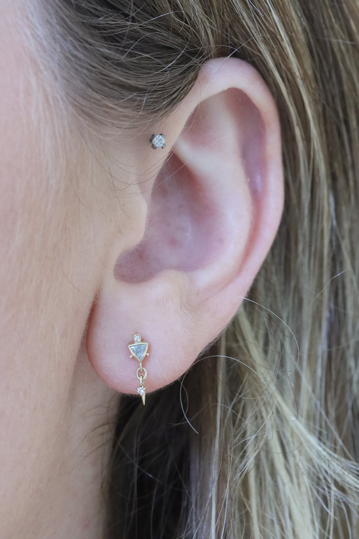 Woman wearing diamond triangle single earring in 14k gold by Celine Daoust.