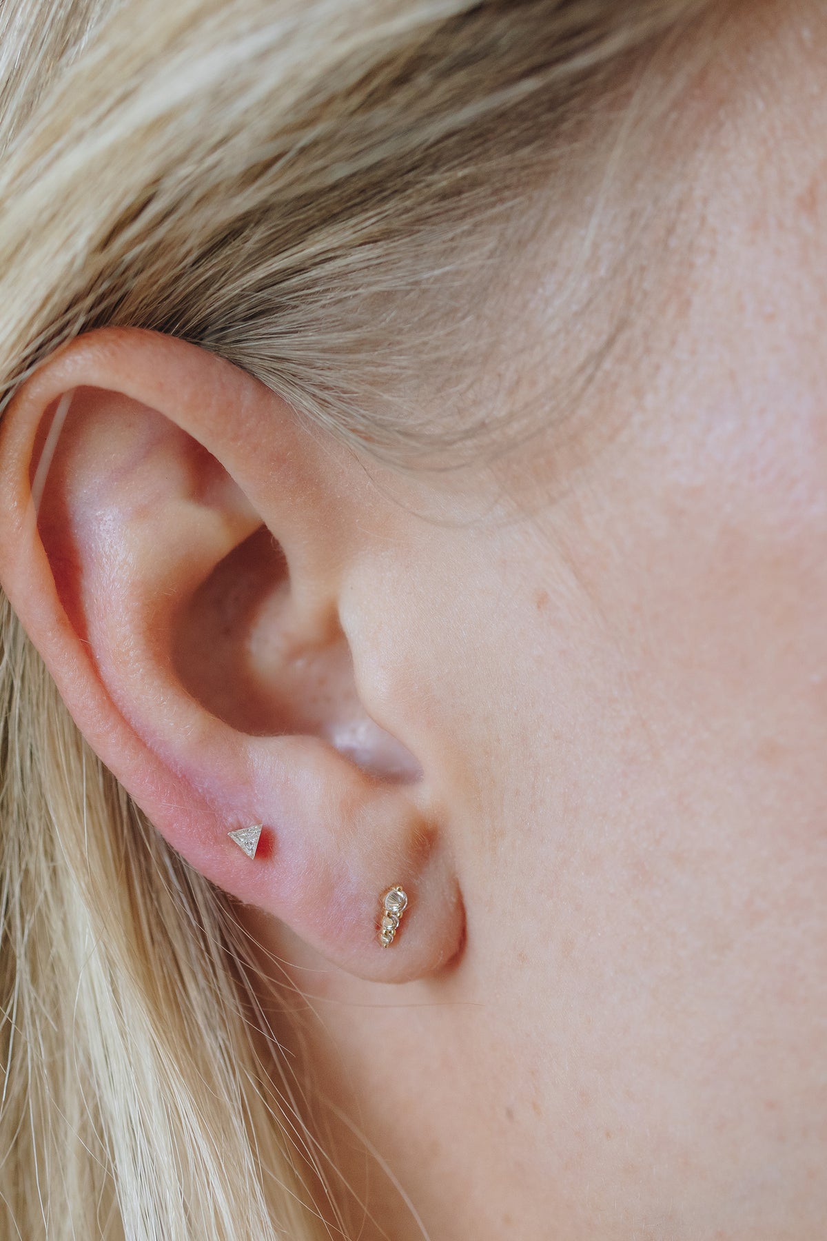 Three inverted round lab diamonds in a graduated curve on a 14K yellow gold threaded flat back stud