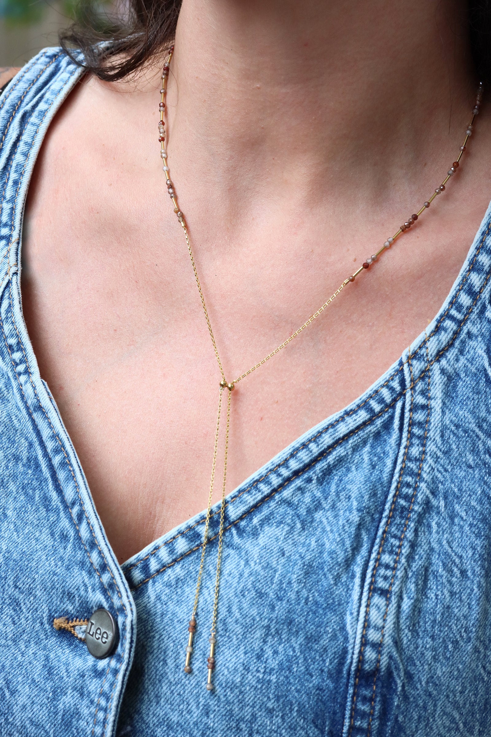 Chocolate zircon lariat necklace with faceted gemstones and liquid gold accents, laid on natural stone